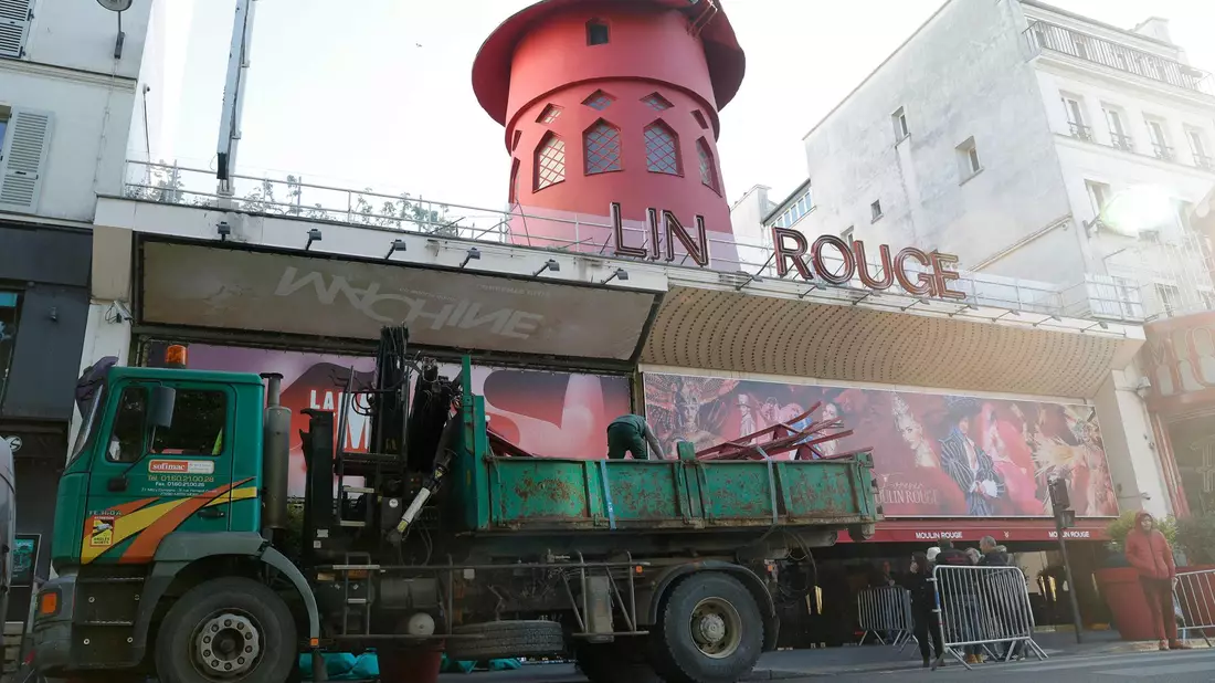Arbeiter sichern den Bereich vor dem Kabarett, nachdem die Flügel des Windrads des «Moulin Rouge» in der Nacht abgestürzt sind. - Bild: Geoffroy Van Der Hasselt/AFP/dpa
