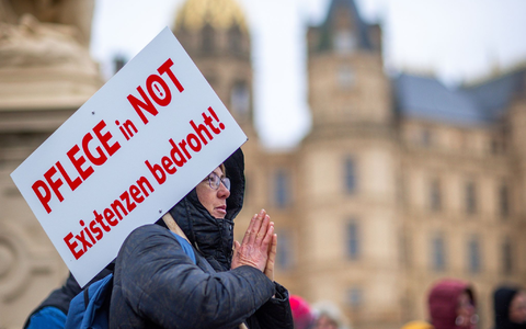 Bei einer Protestaktion vor dem Schweriner Landtag hĂ€lt eine Teilnehmerin ein Schild mit der Aufschrift «Pflege in Not - Existenzen bedroht!». - Foto: Jens BĂŒttner/dpa Bei einer Protestaktion vor dem Schweriner Landtag hĂ€lt eine Teilnehmerin ein Schild mit der Aufschrift «Pflege in Not - Existenzen bedroht!». - Foto: Jens BĂŒttner/dpa