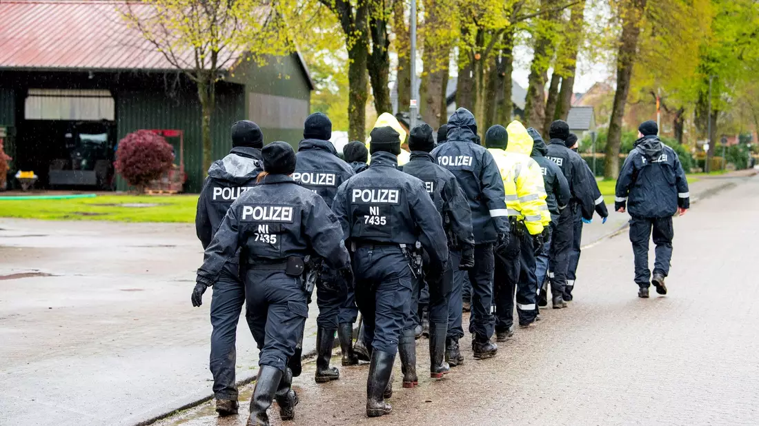 Polizisten gehen auf der Suche nach einem vermissten Jungen durch eine Ortschaft in Niedersachsen. - Bild: Daniel Bockwoldt/dpa