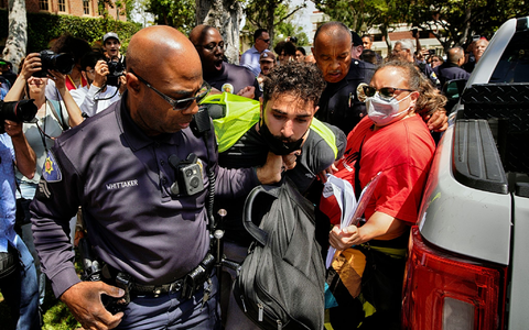 Ein Demonstrant der University of Southern California wird während einer pro-palästinensischen Besetzung des Alumni-Parks in Los Angeles von Beamten des USC Department of Public Safety festgehalten. - Foto: Richard Vogel/AP/dpa