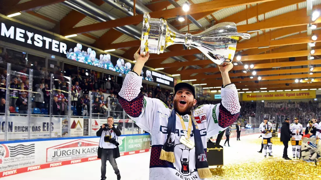 Berlins Yannick Veilleux jubelt nach dem Gewinn der deutschen Eishockey-Meisterschaft mit dem Pokal. - Bild: Carmen Jaspersen/dpa
