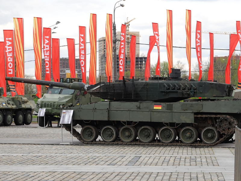 Menschen besichtigen eine Schau zu Kriegstrophäen im Park Pobedy (Park des Sieges) in Moskau. Gezeigt wird Militärtechnik aus verschiedenen westlichen Ländern und der Ukraine. Im Hintergrund zu sehen sind rote Fahnen mit der Aufschrift Pobeda! (auf Deutsch: Sieg). - Foto: Ulf Mauder/dpa