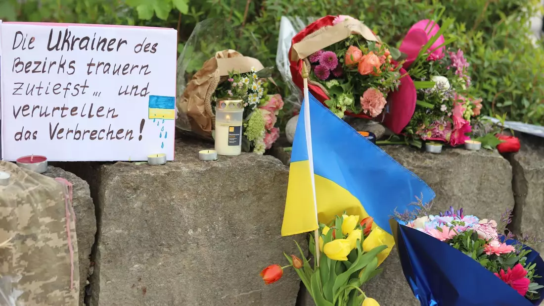 Am Gelände eines Einkaufszentrums, an dem zwei Männer aus der Ukraine getötet worden sind, wurden Blumen niedergelegt sowie eine kleine ukrainische Flagge aufgestellt. - Bild: Constanze Wilz/dpa
