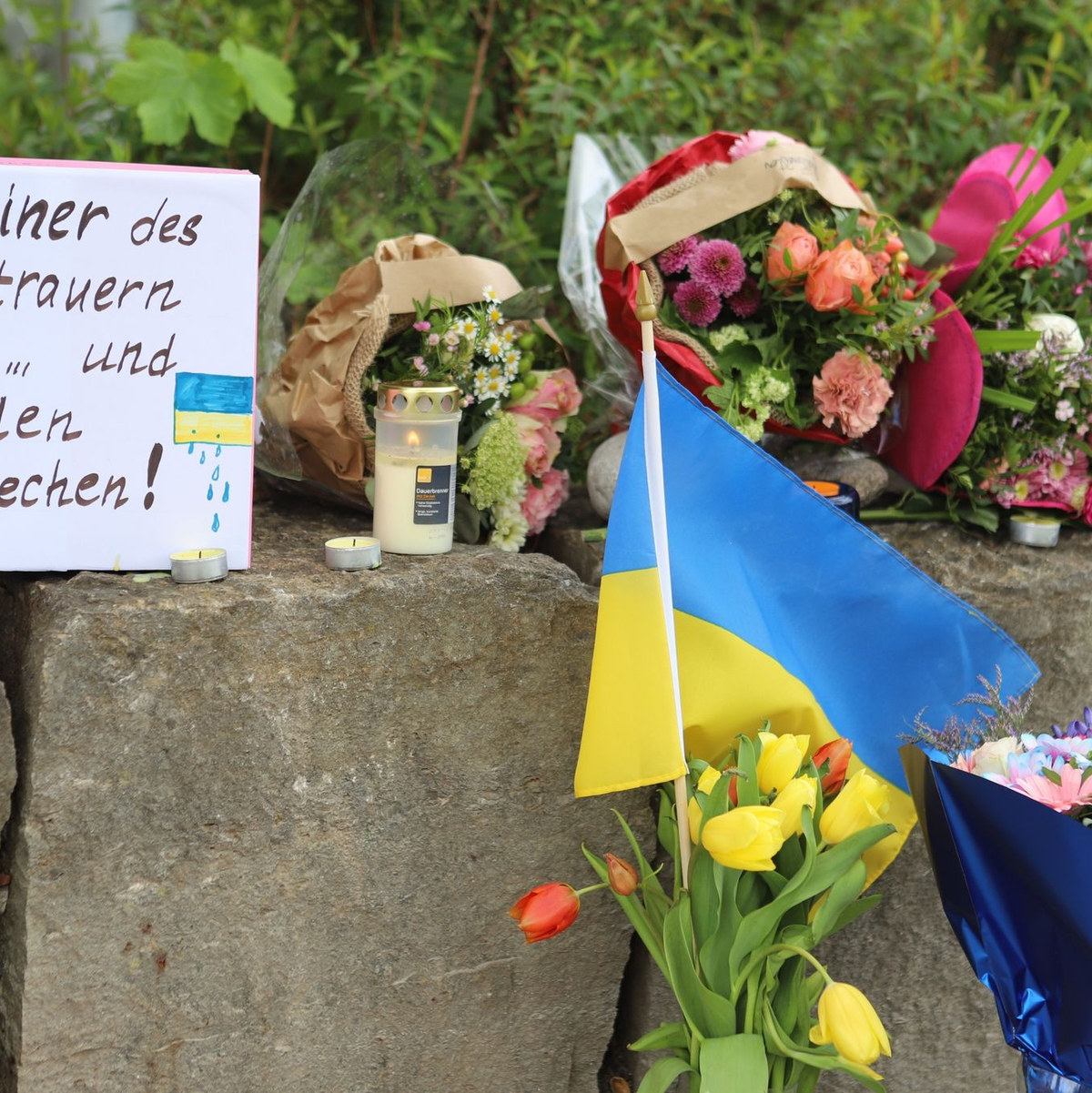 Am Gelände eines Einkaufszentrums, an dem zwei Männer aus der Ukraine getötet worden sind, wurden Blumen niedergelegt sowie eine kleine ukrainische Flagge aufgestellt. - Foto: Constanze Wilz/dpa