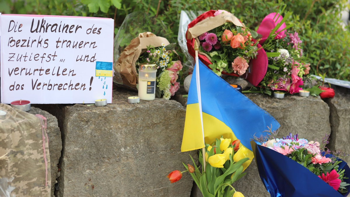 Am Gelände eines Einkaufszentrums, an dem zwei Männer aus der Ukraine getötet worden sind, wurden Blumen niedergelegt sowie eine kleine ukrainische Flagge aufgestellt. - Foto: Constanze Wilz/dpa