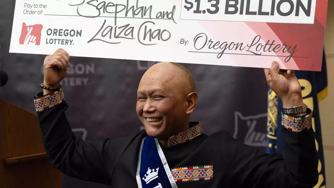 Cheng Saephan hält einen Riesencheck in Höhe von 1,3 Milliarden Dollar in die Höhe. - Bild: Jenny Kane/AP/dpa