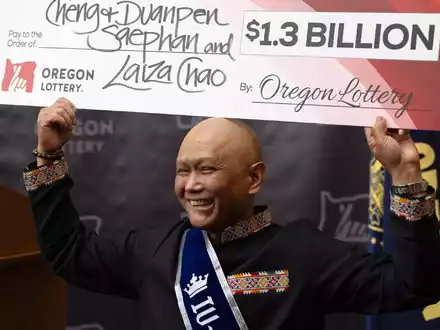 Cheng Saephan hält einen Riesencheck in Höhe von 1,3 Milliarden Dollar in die Höhe. - Foto: Jenny Kane/AP/dpa