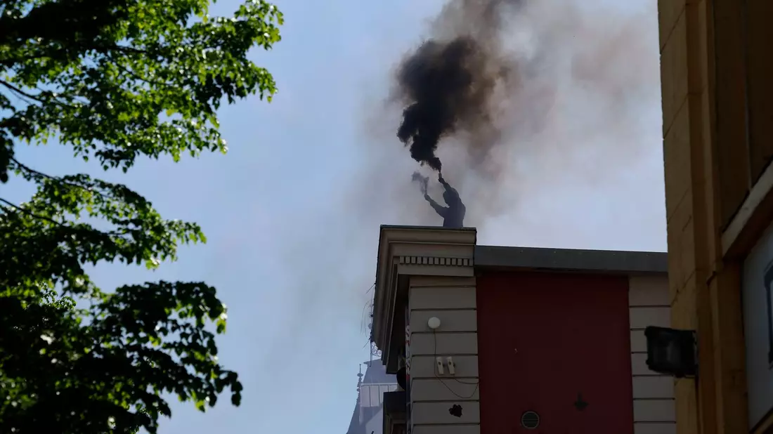 Ein Vermummter brennt auf dem Dach der Roten Flora in Hamburg Pyrotechnik ab. - Bild: Axel Heimken/dpa