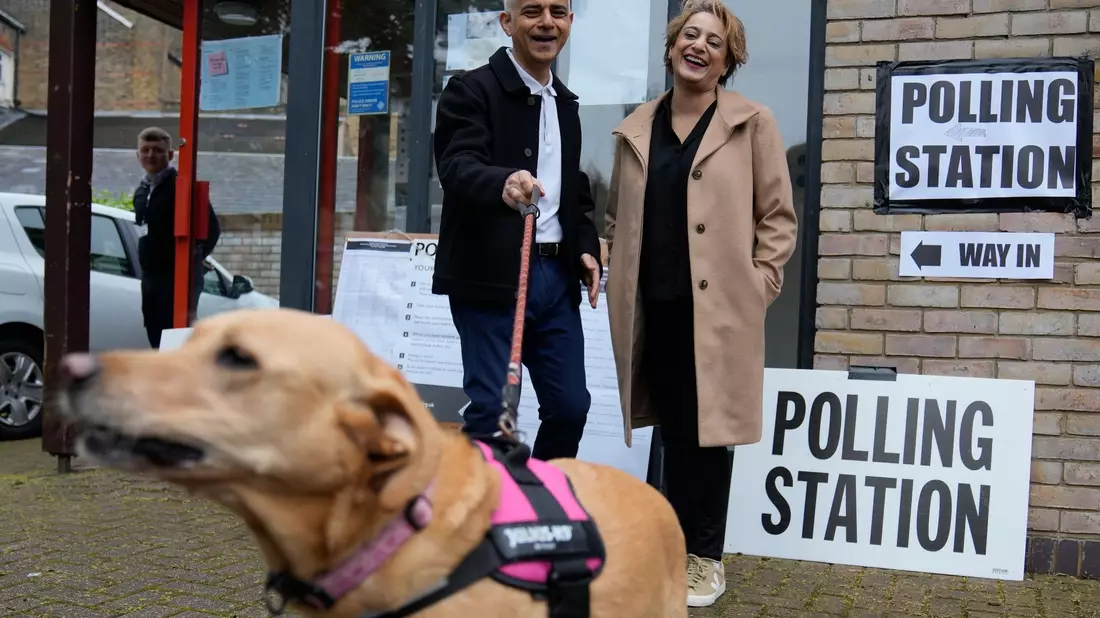 Londons Bürgermeister Sadiq Khan kommt mit seiner Frau Saadiya Ahmed und dem gemeinsamen Hund zur Stimmabgabe. - Bild: Kin Cheung/AP