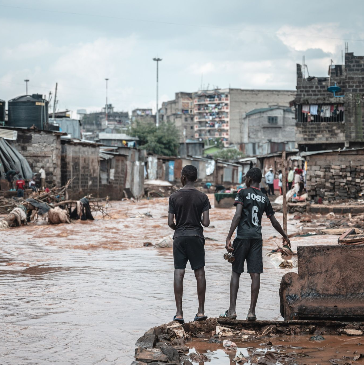 Menschen stehen am Ufer eines überfluteten Flusses in den Mathare-Slums in Nairobi. - Foto: Wang Guansen/XinHua/dpa