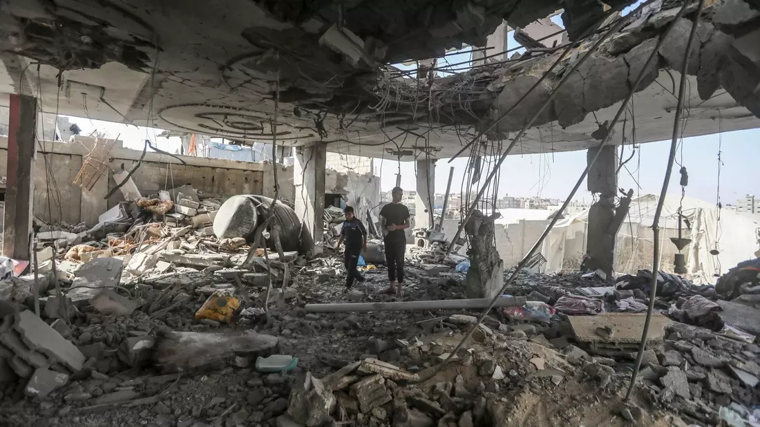 Palästinenser stehen in den Trümmern eines Hauses nach einem israelischen Luftangriff, bei dem mehrere Menschen getötet wurden. - Bild: Ismael Abu Dayyah/AP/dpa