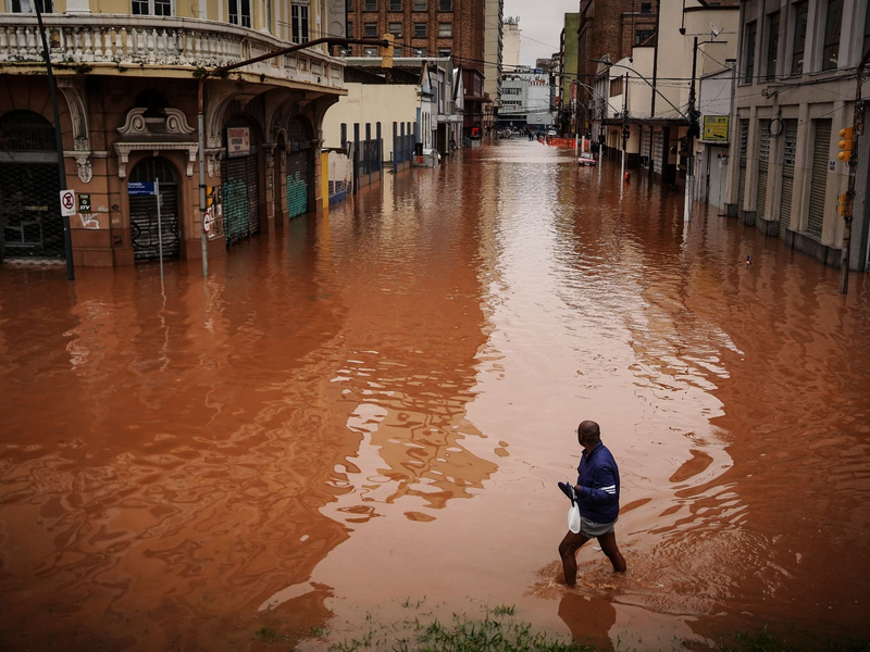 Ein Mann watet in Porto Alegre im brasilianischen Bundesstaat Rio Grande do Sul durch ein von schweren RegenfĂ€llen ĂŒberschwemmtes Gebiet. - Foto: Carlos Macedo/AP/dpa