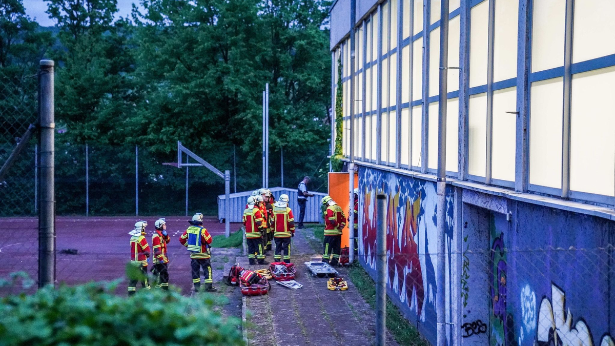 Rettungskräfte stehen vor einer Turnhalle. Vier Kinder sind durch das Dach einer Sporthalle gefallen. - Foto: Kohls/SDMG/dpa