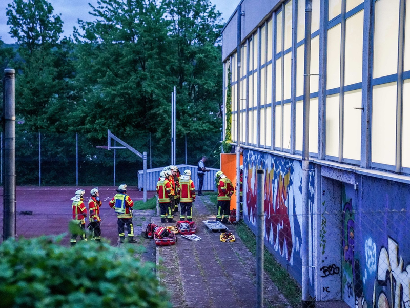 Rettungskräfte stehen vor einer Turnhalle. Vier Kinder sind durch das Dach einer Sporthalle gefallen. - Foto: Kohls/SDMG/dpa