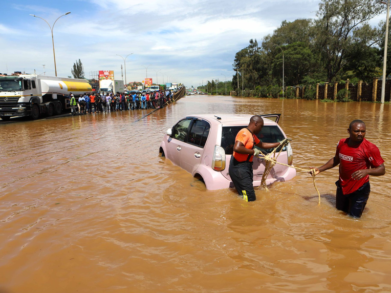 Menschen in Nairobi, die im Hochwasser ein Auto ziehen. - Foto: Joy Nabukewa/XinHua/dpa