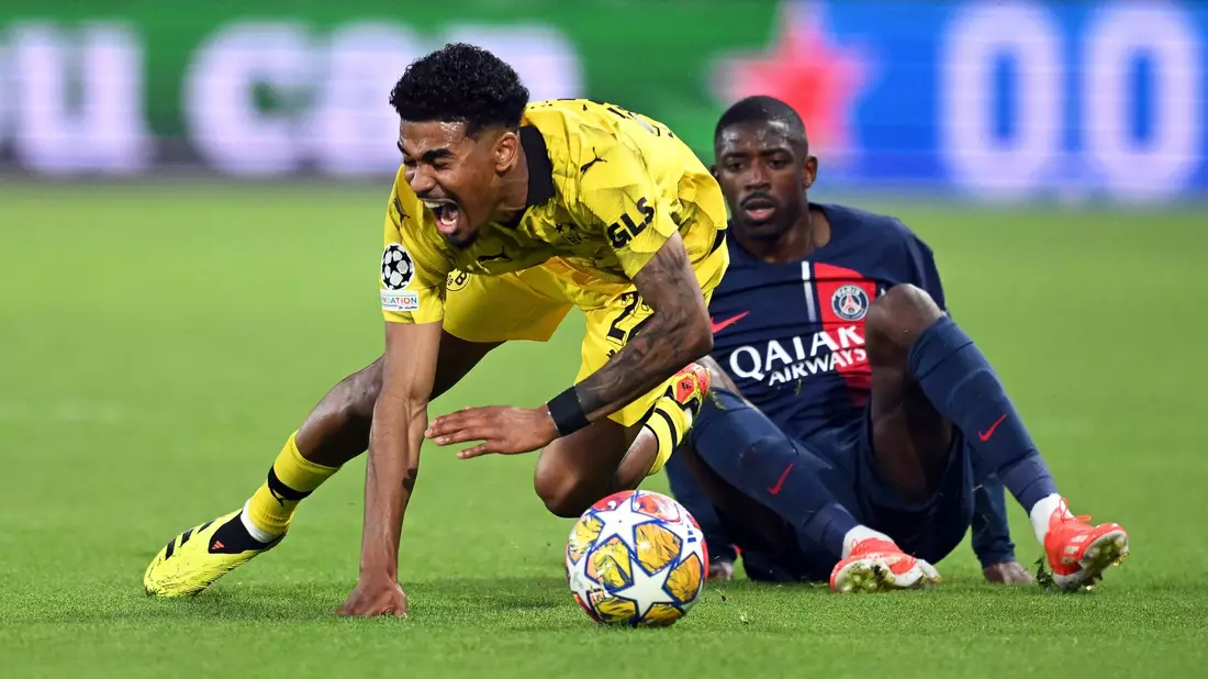 BVB-Verteidiger Ian Maatsen (l) wird von Ousmane Dembelé zu Fall gebracht. - Bild: Robert Michael/dpa