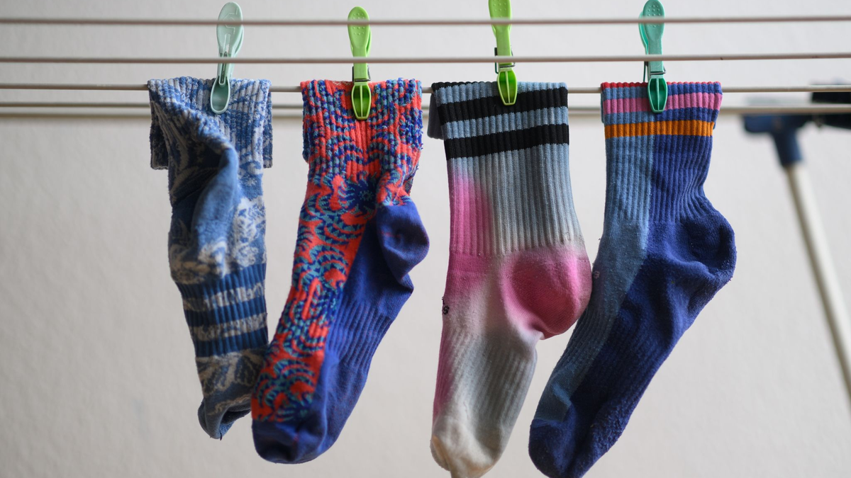 Bunte Socken hängen auf einem Wäscheständer. Am 9. Mai ist Tag der verschwundenen Socken. - Foto: Robert Michael/dpa