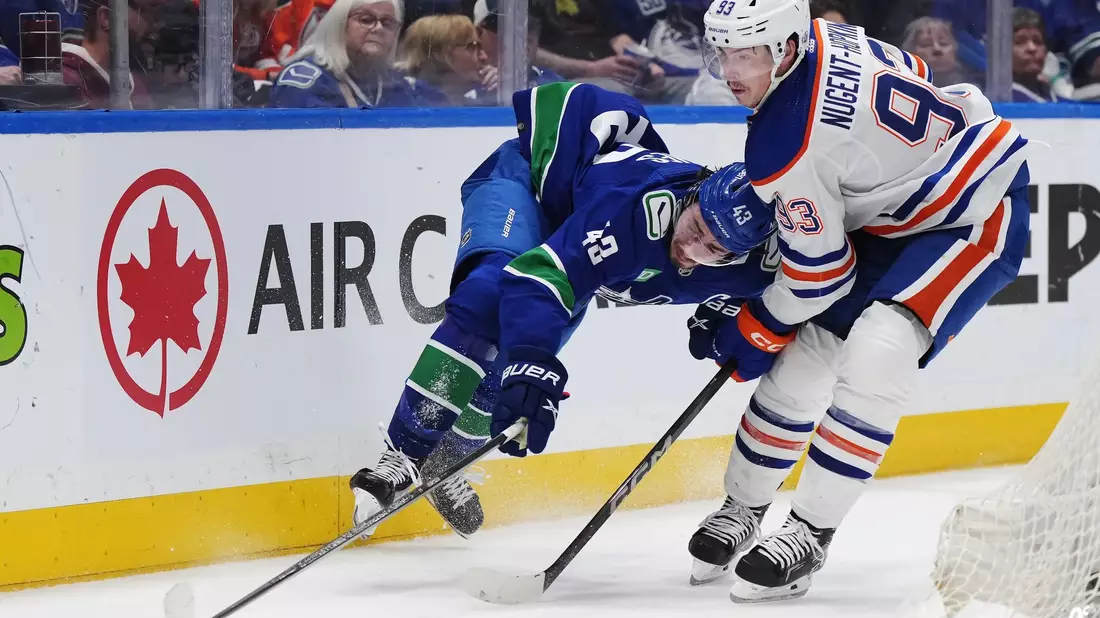 Quinn Hughes von den Vancouver Canucks wird von Ryan Nugent-Hopkins von den Edmonton Oilers zu Fall gebracht. - Bild: Darryl Dyck/The Canadian Press via AP/dpa