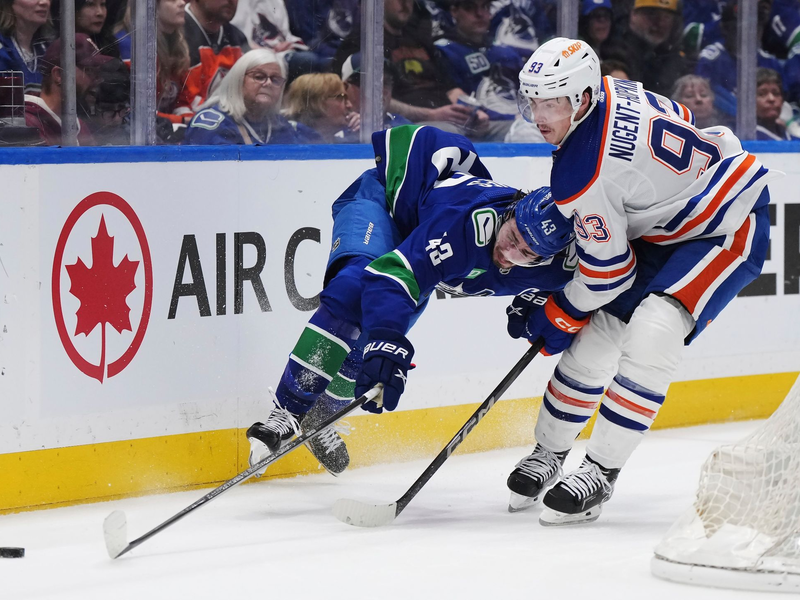 Quinn Hughes von den Vancouver Canucks wird von Ryan Nugent-Hopkins von den Edmonton Oilers zu Fall gebracht. - Foto: Darryl Dyck/The Canadian Press via AP/dpa