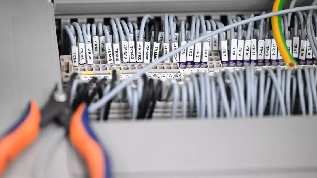Kabelstränge liegen in einer Produktionshalle: Das Geschäftsklima in der deutschen Elektro- und Digitalindustrie ist zurückgefallen. - Bild: Bernd Weißbrod/dpa