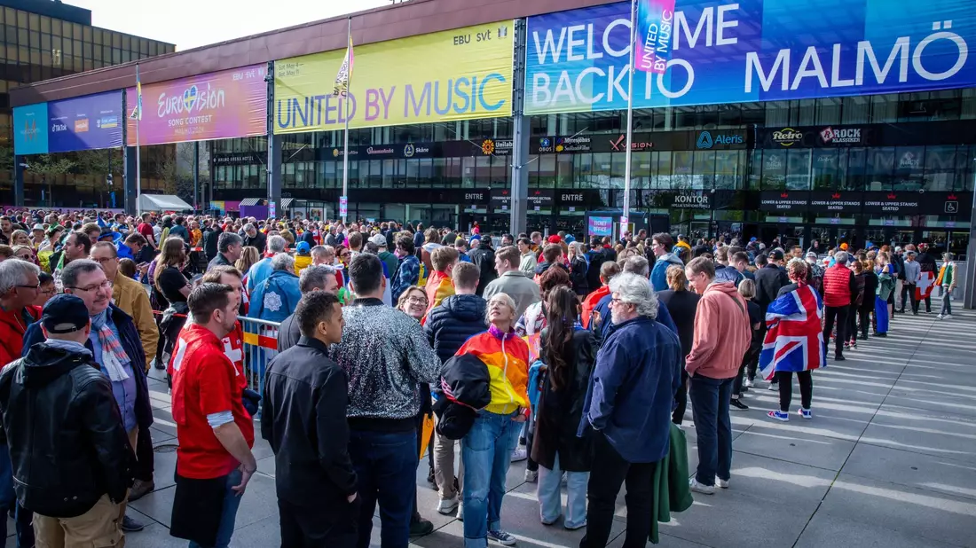 Musikfans stehen vor Beginn des Finales des Eurovision Song Contest 2024 vor der Malmö Arena. - Bild: Jens Büttner/dpa