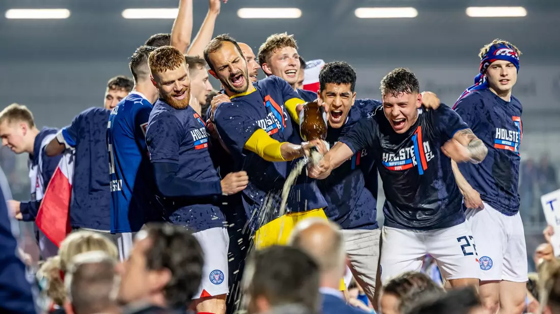 Die Spieler von Kiel feiern mit den Fans gemeinsam den Aufstieg. - Bild: Axel Heimken/dpa