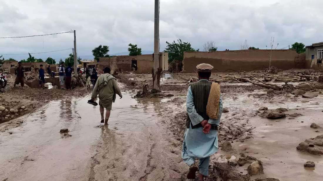 Menschen in der Nähe ihrer beschädigten Häuser nach Überschwemmungen in der nordafghanischen Provinz Baghlan. - Bild: Mehrab Ibrahimi/AP/dpa