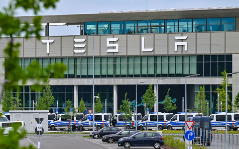 Polizeifahrzeuge stehen am Samstagvormittag vor dem Haupteingang des Tesla-Werks in Grünheide. - Foto: Patrick Pleul/dpa