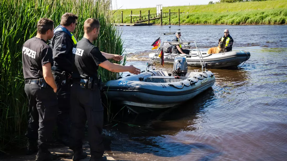 Einsatzkräfte der Polizei fahren bei der Suche nach dem vermissten Arian mit Spürhunden auf Schlauchbooten über die Oste. - Bild: Sina Schuldt/dpa