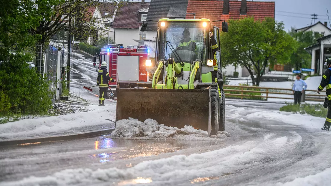 Einsatzkräfte der Feuerwehr räumen nach einem Hagelscheuer eine Straße in Söhnstetten im Landkreis Heidenheim (Baden-Württemberg). - Bild: Jason Tschepljakow/dpa