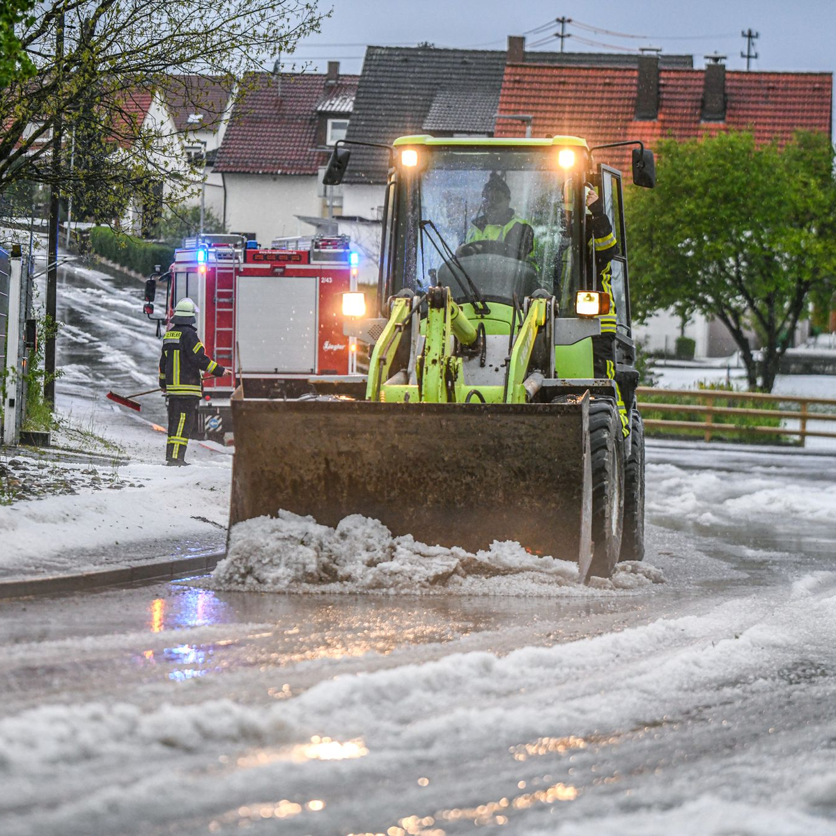 Einsatzkräfte der Feuerwehr räumen nach einem Hagelscheuer eine Straße in Söhnstetten im Landkreis Heidenheim (Baden-Württemberg). - Foto: Jason Tschepljakow/dpa