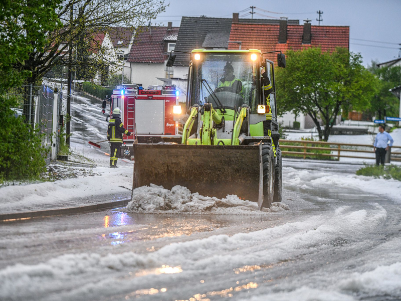Einsatzkräfte der Feuerwehr räumen nach einem Hagelscheuer eine Straße in Söhnstetten im Landkreis Heidenheim (Baden-Württemberg). - Foto: Jason Tschepljakow/dpa