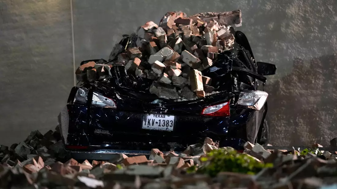 Ein Auto, das von herabfallenden Ziegeln einer umgestürzten Hauswand zerquetscht wurde, steht auf einem Parkplatz in der Innenstadt von Houston. - Bild: David J. Phillip/AP/dpa