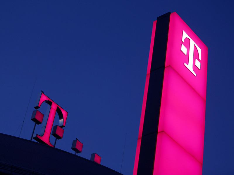 Das Logo der Deutschen Telekom leuchtet auf dem Dach der Unternehmenszentrale. - Foto: Oliver Berg/dpa