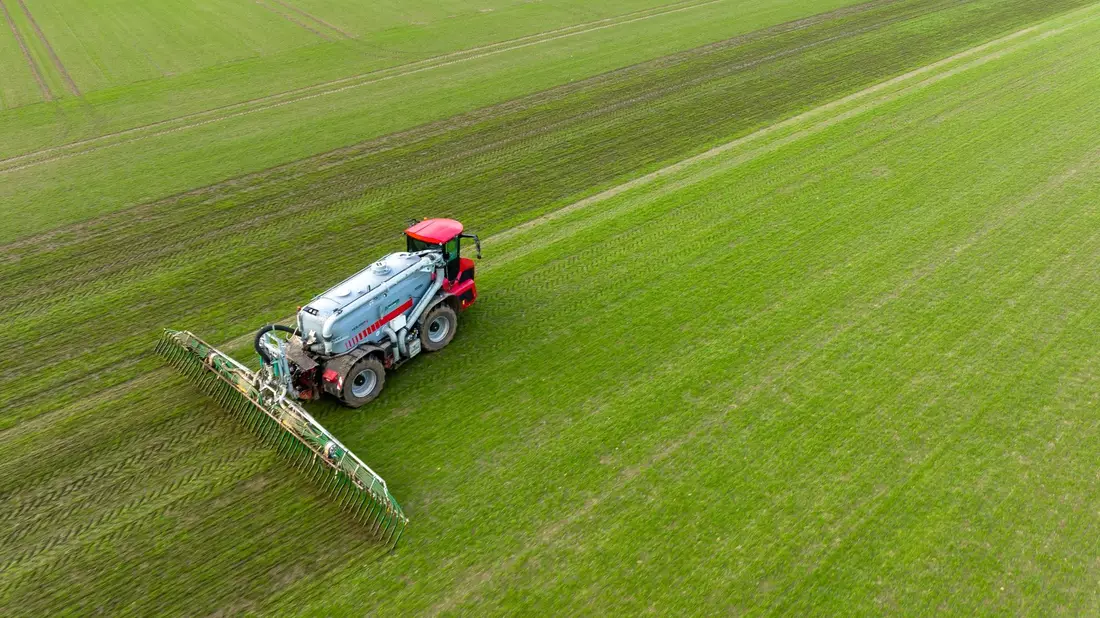 Ein Landwirt bringt mit seinem Gespann Gülle im sogenannten Schleppschuh Verfahren auf einem Feld aus. - Bild: Philipp Schulze/dpa
