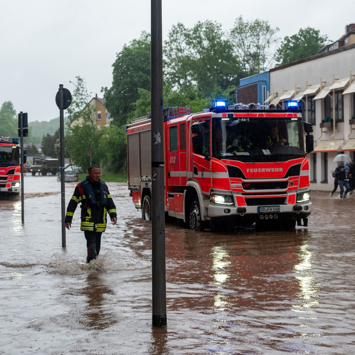 Feuerwehrleute bewegen sich durch das Hochwasser in Saarbrücken. - Foto: Harald Tittel/dpa