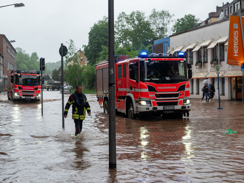 Feuerwehrleute bewegen sich durch das Hochwasser in Saarbrücken. - Foto: Harald Tittel/dpa