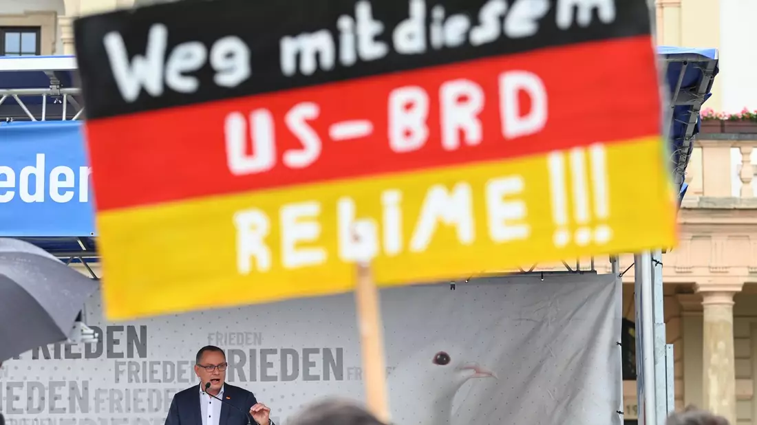 Ein antiamerikanisches Plakat auf einer AfD-Kundgebung mit Bundessprecher Tino Chrupalla in Magdeburg (Archivbild). - Bild: Heiko Rebsch/dpa