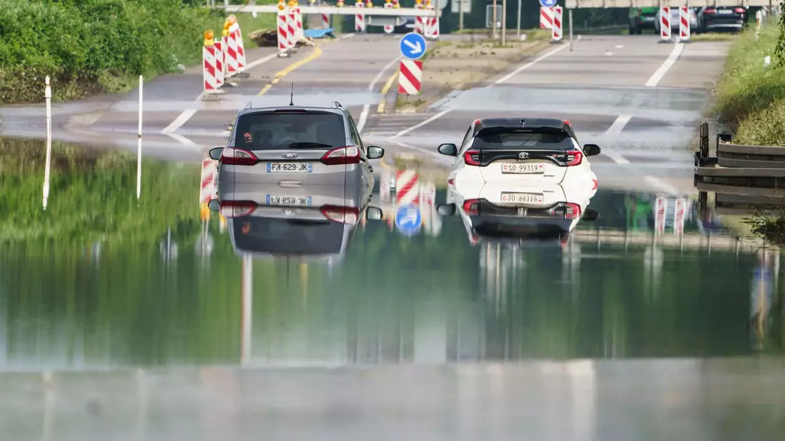 Zwei Autos stehen unter einer Saarbrücke in Saarbrücken im Hochwasser. - Bild: Andreas Arnold/dpa