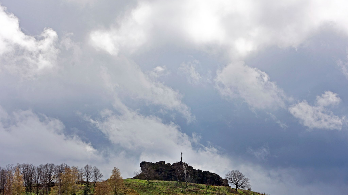 Dunkle Wolken ziehen über die Gegensteine im Harzvorland. - Foto: Matthias Bein/dpa