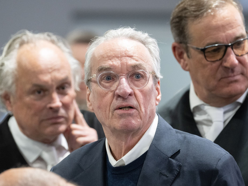 Zum Prozessauftakt gegen die mutmaßliche «Reichsbürger»-Gruppe steht der Hauptangeklagte Heinrich XIII. Prinz Reuß (M) zwischen seinen Verteidigern im Gerichtssaal. - Foto: Boris Roessler/dpa-Pool/dpa