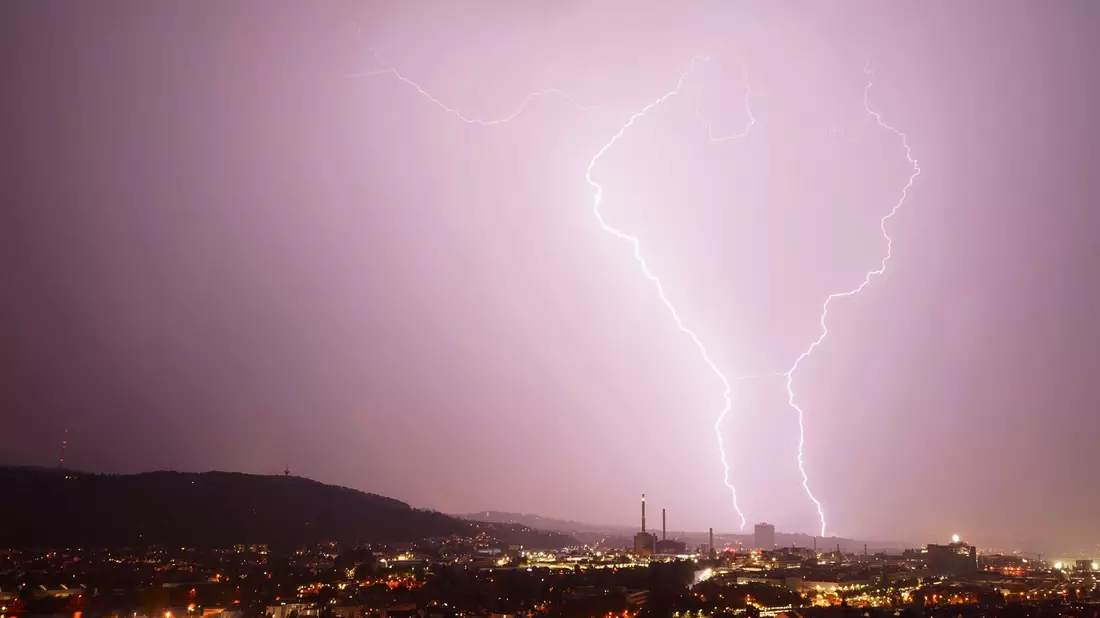 Zwei Blitze entladen sich bei einem  Gewitter über Stuttgart. - Bild: Andreas Rosar/dpa
