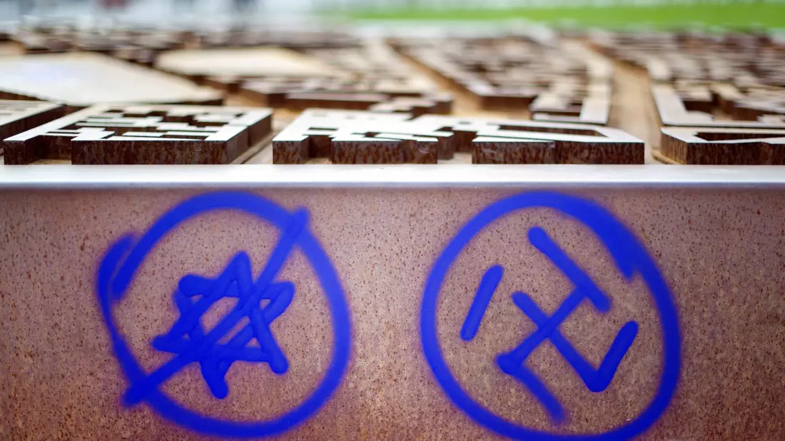 Ein Hakenkreuz und ein durchgestrichener Davidstern sind an einer Gedenkstätte zu sehen. - Bild: Daniel Reinhardt/Deutsche Presse-Agentur GmbH/dpa
