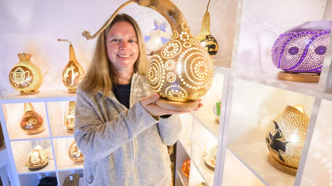 Virginia Lauterbach präsentiert eine ihrer handgefertigten Kürbislampen in der Kalebassenmanufaktur in Bückeburg. - Bild: Julian Stratenschulte/dpa
