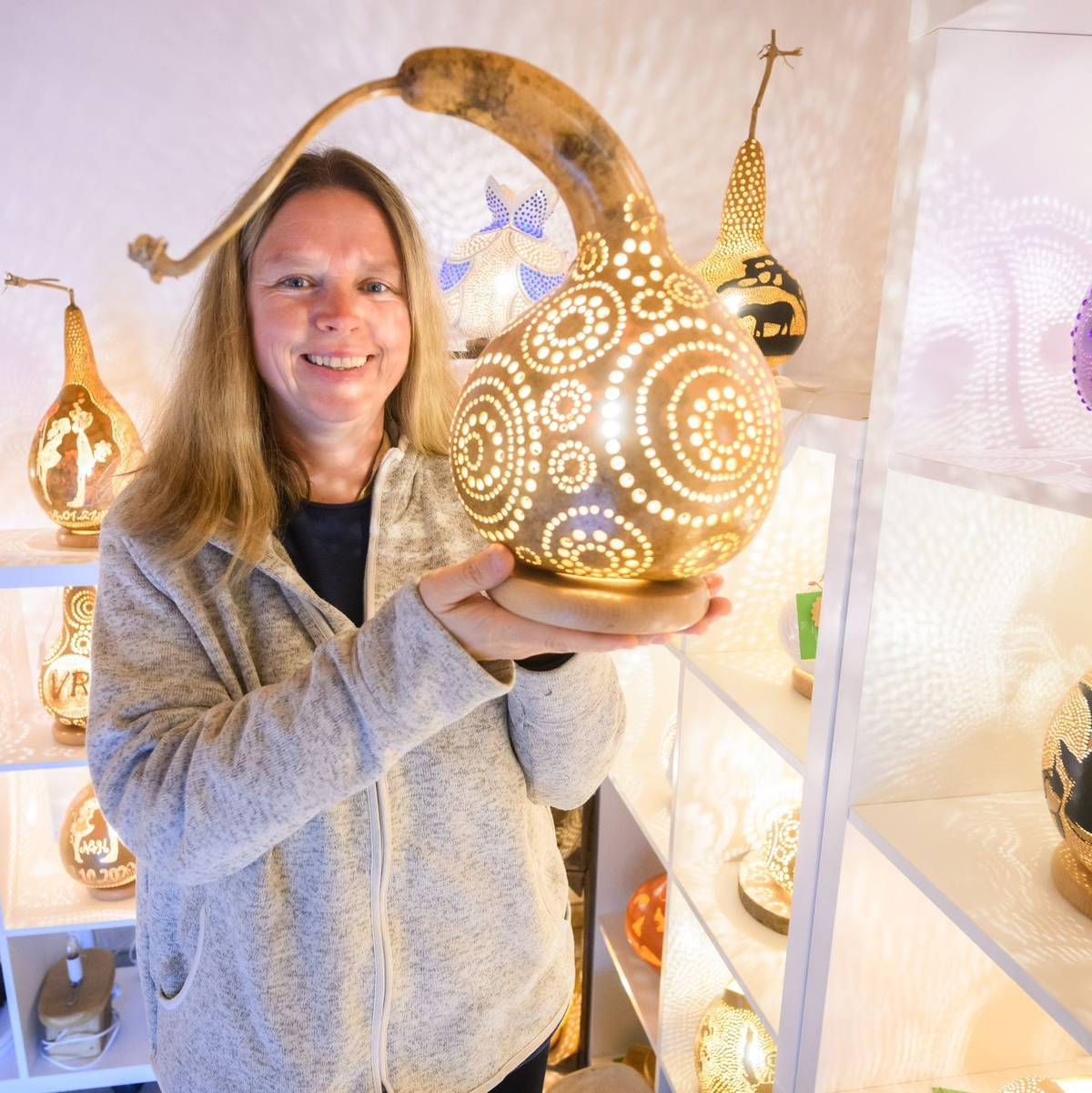 Virginia Lauterbach präsentiert eine ihrer handgefertigten Kürbislampen in der Kalebassenmanufaktur in Bückeburg. - Foto: Julian Stratenschulte/dpa
