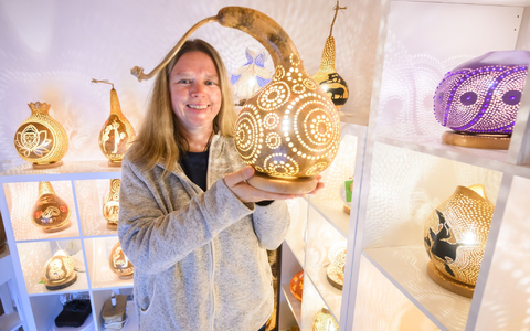 Virginia Lauterbach präsentiert eine ihrer handgefertigten Kürbislampen in der Kalebassenmanufaktur in Bückeburg. - Foto: Julian Stratenschulte/dpa