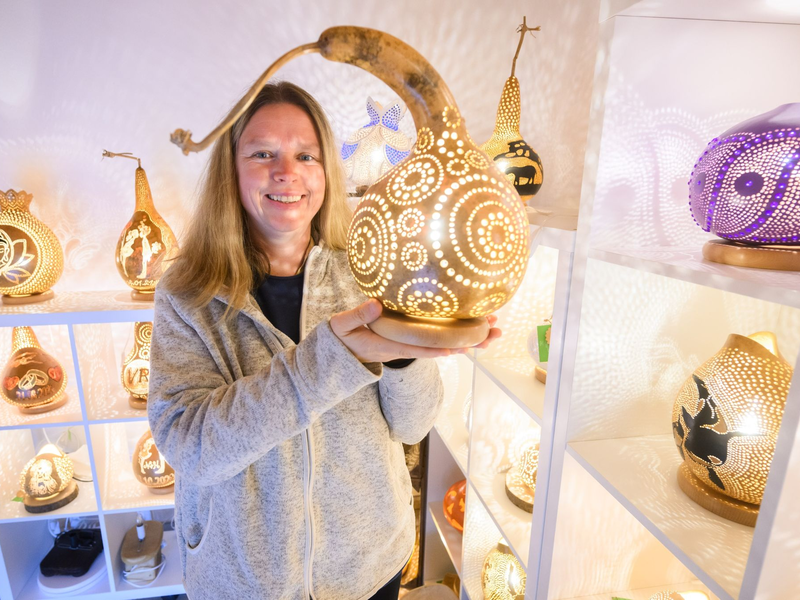 Virginia Lauterbach präsentiert eine ihrer handgefertigten Kürbislampen in der Kalebassenmanufaktur in Bückeburg. - Foto: Julian Stratenschulte/dpa
