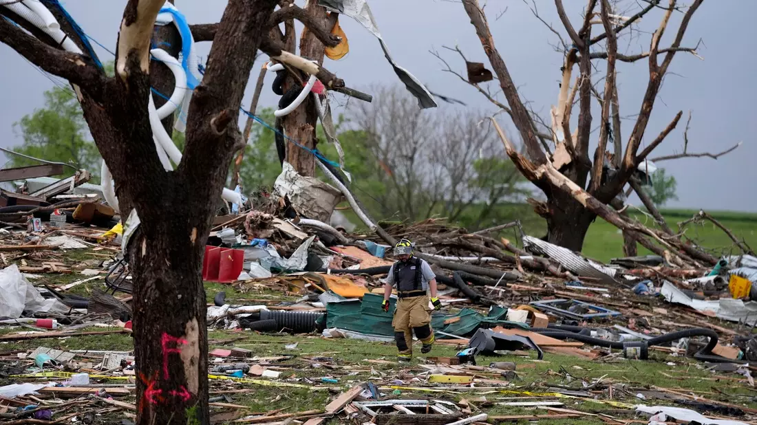 Ein Feuerwehrmann geht in Greenfield, Iowa, durch die Trümmer von Häusern, die vo einem Tornado zerstört wurden. - Bild: Charlie Neibergall/AP/dpa