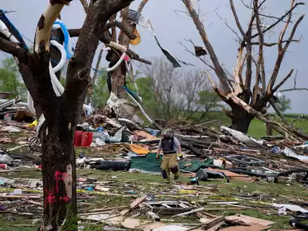 Ein Feuerwehrmann geht in Greenfield, Iowa, durch die Trümmer von Häusern, die vo einem Tornado zerstört wurden. - Foto: Charlie Neibergall/AP/dpa