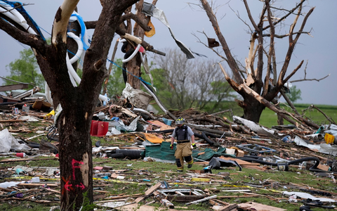 Ein Feuerwehrmann geht in Greenfield, Iowa, durch die Trümmer von Häusern, die vo einem Tornado zerstört wurden. - Foto: Charlie Neibergall/AP/dpa
